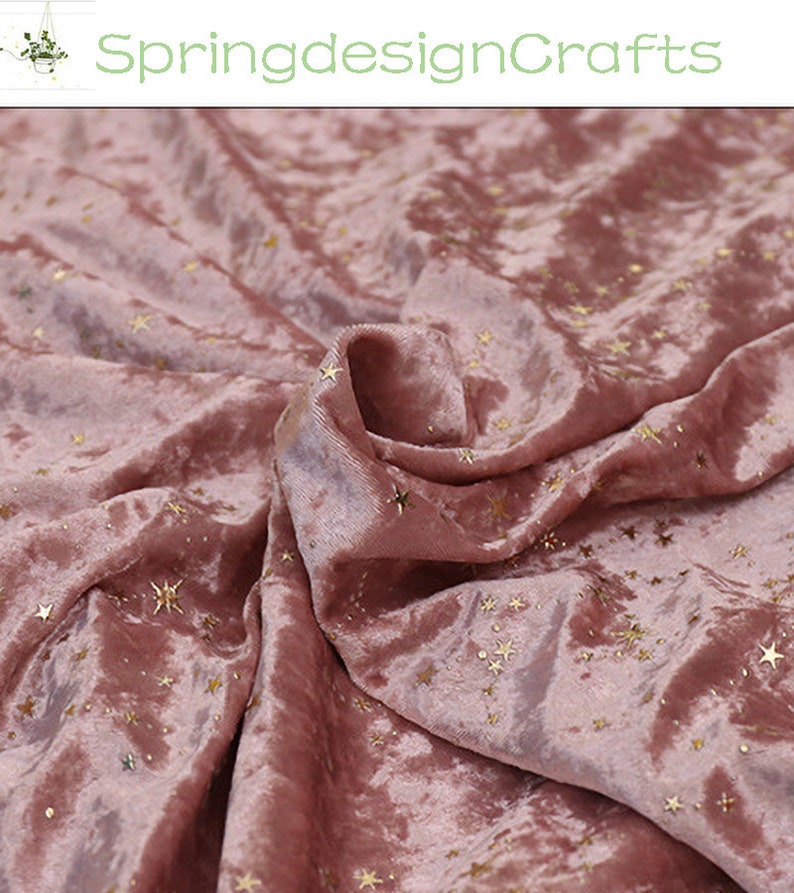May include: Dusty rose velvet fabric with gold star accents. The fabric is draped, showing the texture and sheen of the material. The text "SpringdesignCrafts" is in the upper left corner.