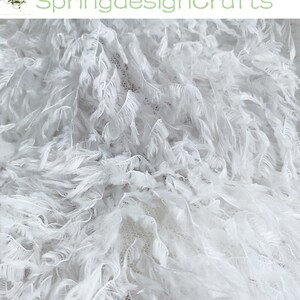 May include: White feather trim fabric with a soft, fluffy texture. The fabric is perfect for adding a touch of elegance to any project.