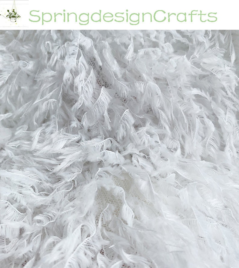 May include: White feather trim fabric with a soft, fluffy texture. The fabric is perfect for adding a touch of elegance to any project.