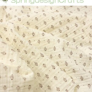 May include: Cream-colored fabric with a repeating pattern of small, dark brown floral-like shapes. The fabric is slightly wrinkled, suggesting a soft texture. The text "SpringdesignCrafts" is visible in the upper left corner.
