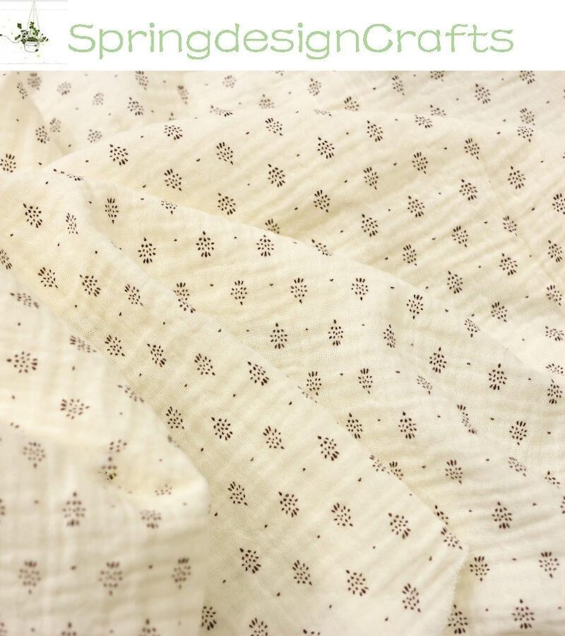 May include: Cream-colored fabric with a repeating pattern of small, dark brown floral-like shapes. The fabric is slightly wrinkled, suggesting a soft texture. The text "SpringdesignCrafts" is visible in the upper left corner.