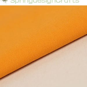 May include: A solid orange fabric with a visible woven texture. The text SpringdesignCrafts is displayed in light green at the top of the image. The fabric is folded diagonally across the frame, showing a consistent, vibrant orange colour.