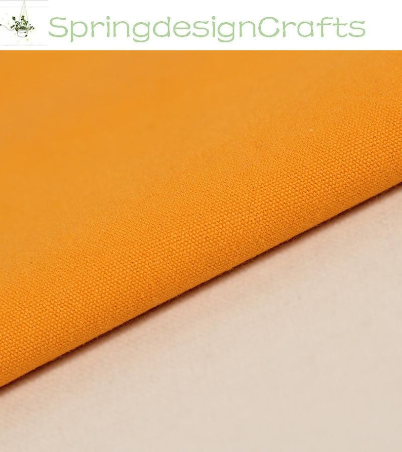 May include: A solid orange fabric with a visible woven texture. The text SpringdesignCrafts is displayed in light green at the top of the image. The fabric is folded diagonally across the frame, showing a consistent, vibrant orange colour.