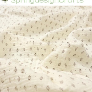 May include: Cream-colored fabric with a repeating pattern of small, dark brown floral or leaf-like shapes. The fabric is soft and textured, with visible folds and wrinkles. The text "SpringdesignCrafts" is in green at the top.