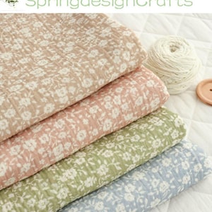 May include: Four folded fabric pieces in shades of tan, pink, green, and blue, each with a white floral pattern. A ball of white yarn and a wooden button are also visible. The text "SpringdesignCrafts" is at the top.