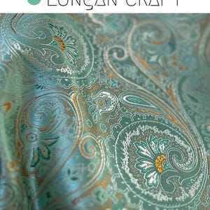 May include: Close-up of a teal paisley fabric with gold and white accents. The fabric has a subtle shimmer and a luxurious feel.