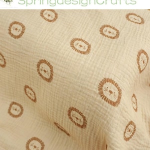 May include: Cream-colored fabric with a repeating pattern of brown lion faces. The fabric has a textured, crinkled appearance. The text "SpringdesignCrafts" is in the upper left corner.
