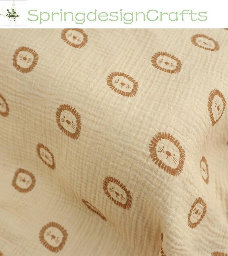 May include: Cream-colored fabric with a repeating pattern of brown lion faces. The fabric has a textured, crinkled appearance. The text "SpringdesignCrafts" is in the upper left corner.
