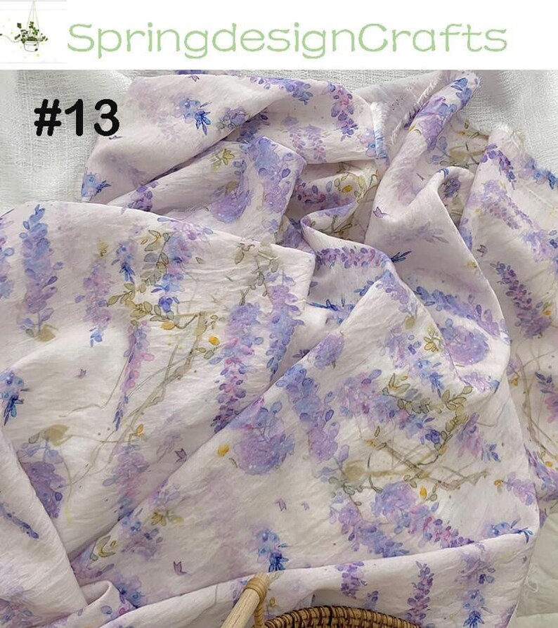 Peut inclure: Tissu blanc avec un motif floral &agrave; l'aquarelle de fleurs de glycine violettes et bleues. Le tissu a un drap&eacute; doux et fluide. Le texte "#13" est visible. Le nom de la boutique "SpringdesignCrafts" est &eacute;galement visible.