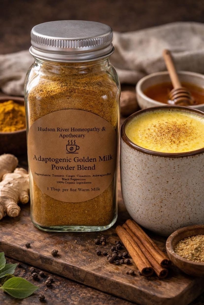 May include: A jar of Adaptogenic Golden Milk Powder Blend, with ingredients including turmeric and ginger, is next to a mug of golden milk. The jar has a label with the text "Hudson River Homeopathy & Apothecary". Cinnamon sticks and honey are also visible.