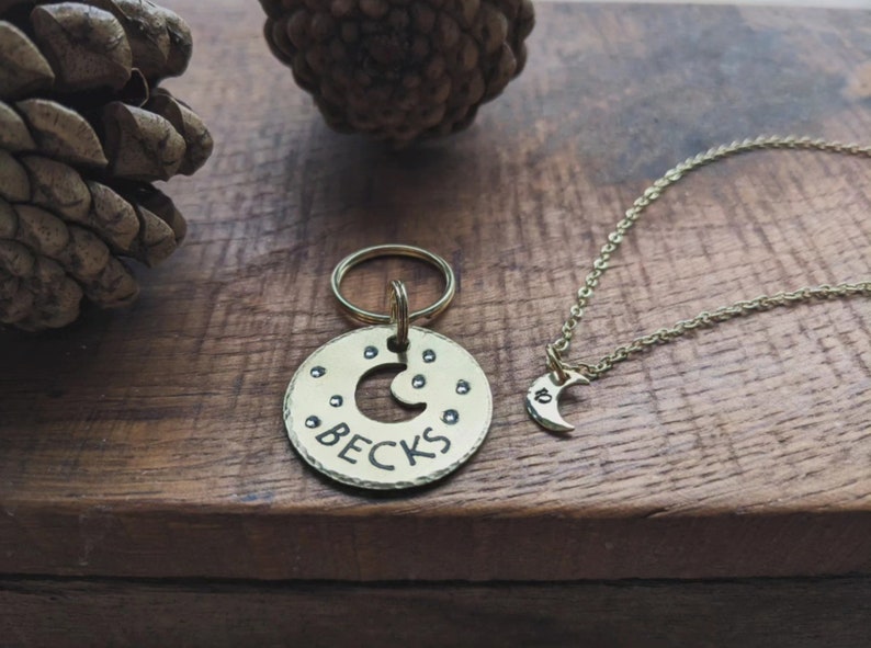 Puede incluir: Un llavero dorado con una etiqueta redonda que presenta un dise&ntilde;o de luna creciente y el nombre "Becks" grabado. Un collar dorado a juego con un colgante de luna creciente m&aacute;s peque&ntilde;o.