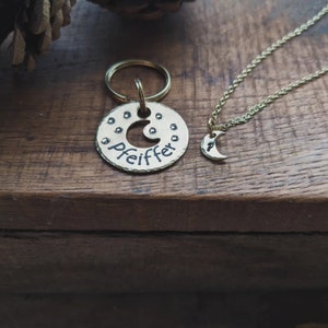 Puede incluir: Un llavero de metal dorado con un dise&ntilde;o de media luna y el nombre "Pfeiffer" grabado en &eacute;l. Tambi&eacute;n se muestra un collar de metal dorado a juego con un colgante de media luna.