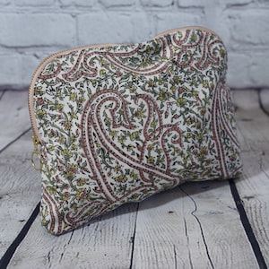 Può includere: Una pochette con cerniera bianca con motivo paisley e un design floreale rosa e verde.