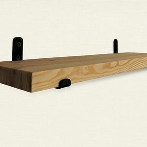 Könnte beinhalten: Ein Holzregal mit schwarzen Metallkonsolen. Das Regal ist aus Naturholz gefertigt und hat einen rustikalen Look.