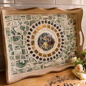 May include: A rectangular wooden serving tray featuring a mosaic inlay of green and white ceramic shards. The center displays a circular scene of figures in period clothing, surrounded by a ring of gold tiles and dark, reflective glass beads.