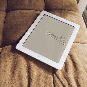May include: A white tablet computer with a light brown screen displaying the text "My Happy Plan" on a brown couch.