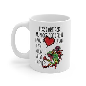 May include: White ceramic mug with a green and red cartoon creature holding a red heart balloon. The mug has the text "Roses are red, Murlocs are green, BRAWLALAWRl, If you know what I mean."