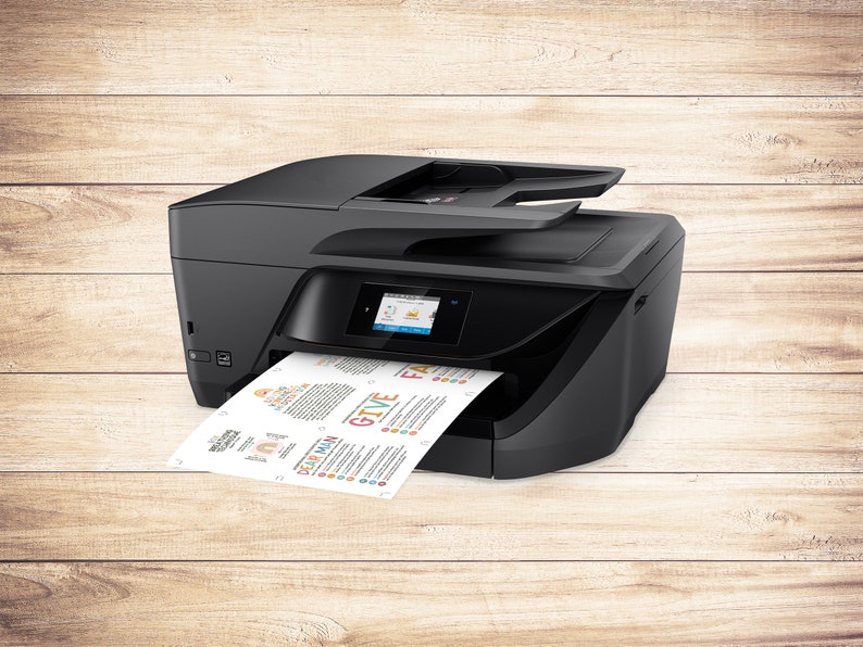 Op de afbeelding: Een zwarte alles-in-&eacute;&eacute;n printer met een papierlade en een kleurenscherm. De printer print een vel papier met kleurrijke tekst en afbeeldingen.