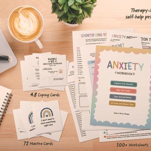 May include: A collection of therapy-inspired self-help printables including an Anxiety Workbook, 48 coping cards, 72 mantra cards, and 100+ worksheets. The workbook cover features a scalloped border and the text Anxiety Workbook with four coloured buttons.