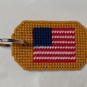 May include: A gold-colored key chain with a small American flag design. The flag is red, white, and blue with a gold border.