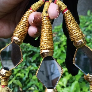 May include: Three gold tassel ornaments with small diamond-shaped mirrors. Each tassel has a gold cord and a red and gold tassel.