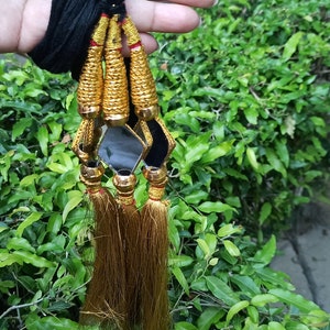 May include: Four gold tassels with black and gold trim and small square mirrors hanging from a black cord.