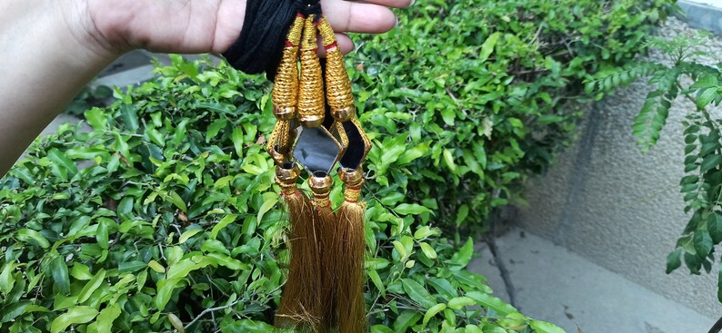 May include: Four gold tassels with black and gold trim and small square mirrors hanging from a black cord.