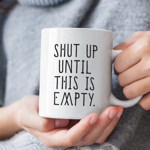 May include: White ceramic coffee mug with black text that reads "Shut up until this is empty."