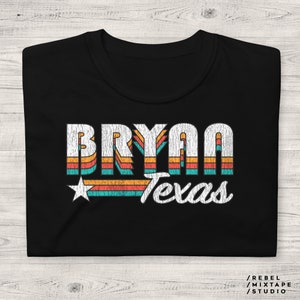 May include: Black t-shirt with a retro-style graphic design featuring the name "Bryan" and the word "Texas" in a colorful striped pattern.