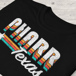 May include: Black t-shirt with a white retro graphic design that says "PHARR Texas" with a star and colorful stripes.
