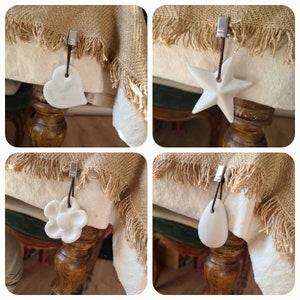 Peut inclure: Quatre clips de table en céramique blanche de formes différentes : un cœur, une étoile, une fleur et une larme. Chaque clip est attaché à un cordon brun et à un clip argenté.