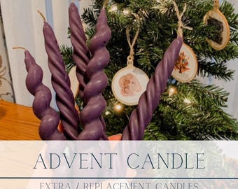 Könnte beinhalten: Fünf gedrehte violette Kerzen mit feinem Drehdesign. Die Kerzen stehen vor einem geschmückten Weihnachtsbaum. Der Text auf dem Bild lautet "ADVENT CANDLE" und "EXTRA / REPLACEMENT CANDLES FINE TWIST".
