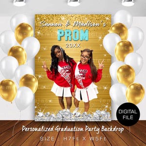 May include: Gold glitter backdrop with the text "Sannon & Madison's PROM 20XX" in black and teal. Two people are standing in front of the backdrop, wearing red and white cheerleading outfits. The backdrop is decorated with white and gold balloons.