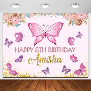 May include: Pink and purple butterfly themed birthday backdrop with gold glitter and the text "Happy 8th Birthday Amisha".