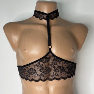 Può includere: Lingerie nera in pizzo con un choker e spalline. Il pizzo ha un motivo floreale.