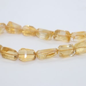 May include: A strand of golden citrine gemstone beads, each bead is faceted and has a rectangular shape.