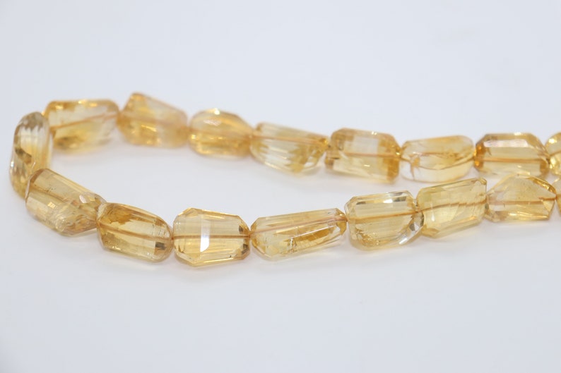 May include: A strand of golden citrine gemstone beads, each bead is faceted and has a rectangular shape.