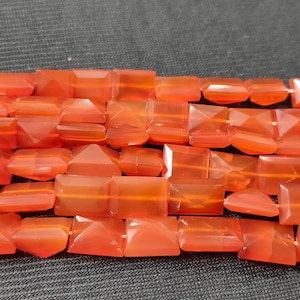 以下が含まれることがあります： 正方形と三角形の混合形状のカーネリアンビーズのストランド。ビーズは鮮やかなオレンジレッドの色で、磨かれた半透明の仕上げになっています。