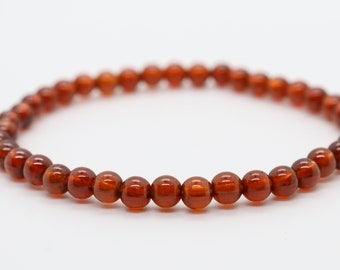 Pode incluir: Um bracelete de pedras preciosas marrons com contas redondas.