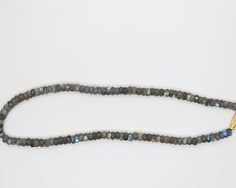 May include: A necklace made of dark gray gemstone beads with a gold clasp.