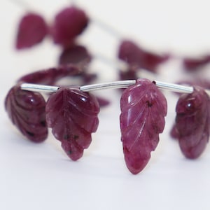 Puede incluir: Una hebra de cuentas de hoja de rubí talladas enhebradas en alambre de plata. Las cuentas son de color rosa intenso y tienen un aspecto natural y orgánico.