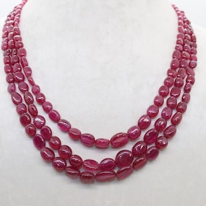 May include: A three-strand necklace made of oval-shaped ruby beads.
