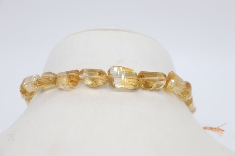 May include: A strand of golden citrine beads, each bead is faceted and has a unique shape. The beads are strung on a clear elastic cord and are ready to be made into a necklace or bracelet.