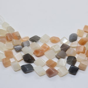 Puede incluir: Una hebra de cuentas de piedra de sol en varios tonos de blanco, gris y melocotón. Las cuentas son facetadas y tienen forma cuadrada.