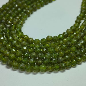 以下が含まれることがあります： 緑色の宝石のビーズが、ファセットカットで丸く、長いネックレスに糸でつながっています。
