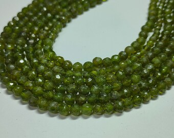 May include: A strand of green gemstone beads, faceted and round, strung together in a long necklace.
