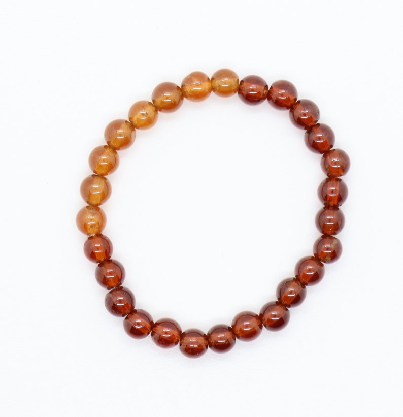 May include: A brown gemstone bracelet with round beads. The beads are a gradient of brown, with the lighter brown beads at the top and the darker brown beads at the bottom.