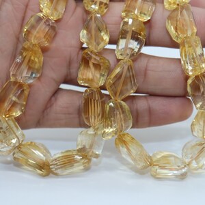 May include: A strand of faceted, golden citrine beads. The beads are a light yellow color and have a smooth, polished finish.