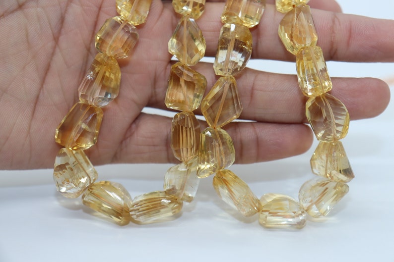 May include: A strand of faceted, golden citrine beads. The beads are a light yellow color and have a smooth, polished finish.