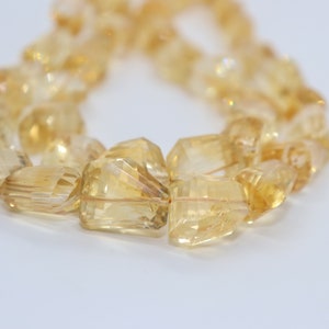 May include: A strand of faceted, golden citrine beads. The beads are irregular in shape and have a translucent, glassy appearance.